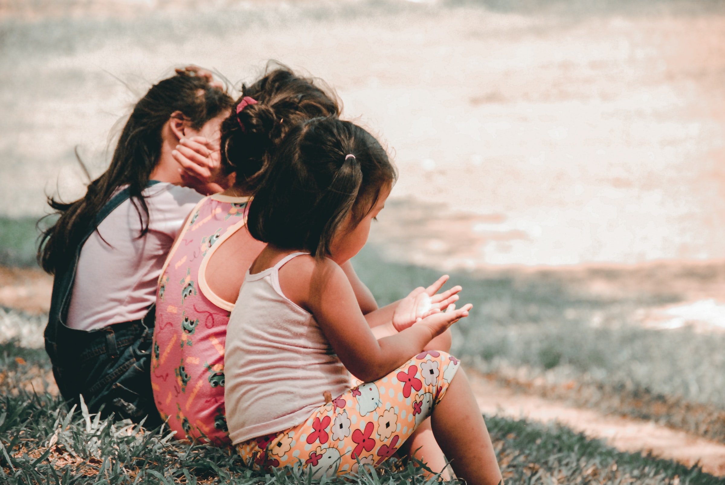 three young girls sitting in grass