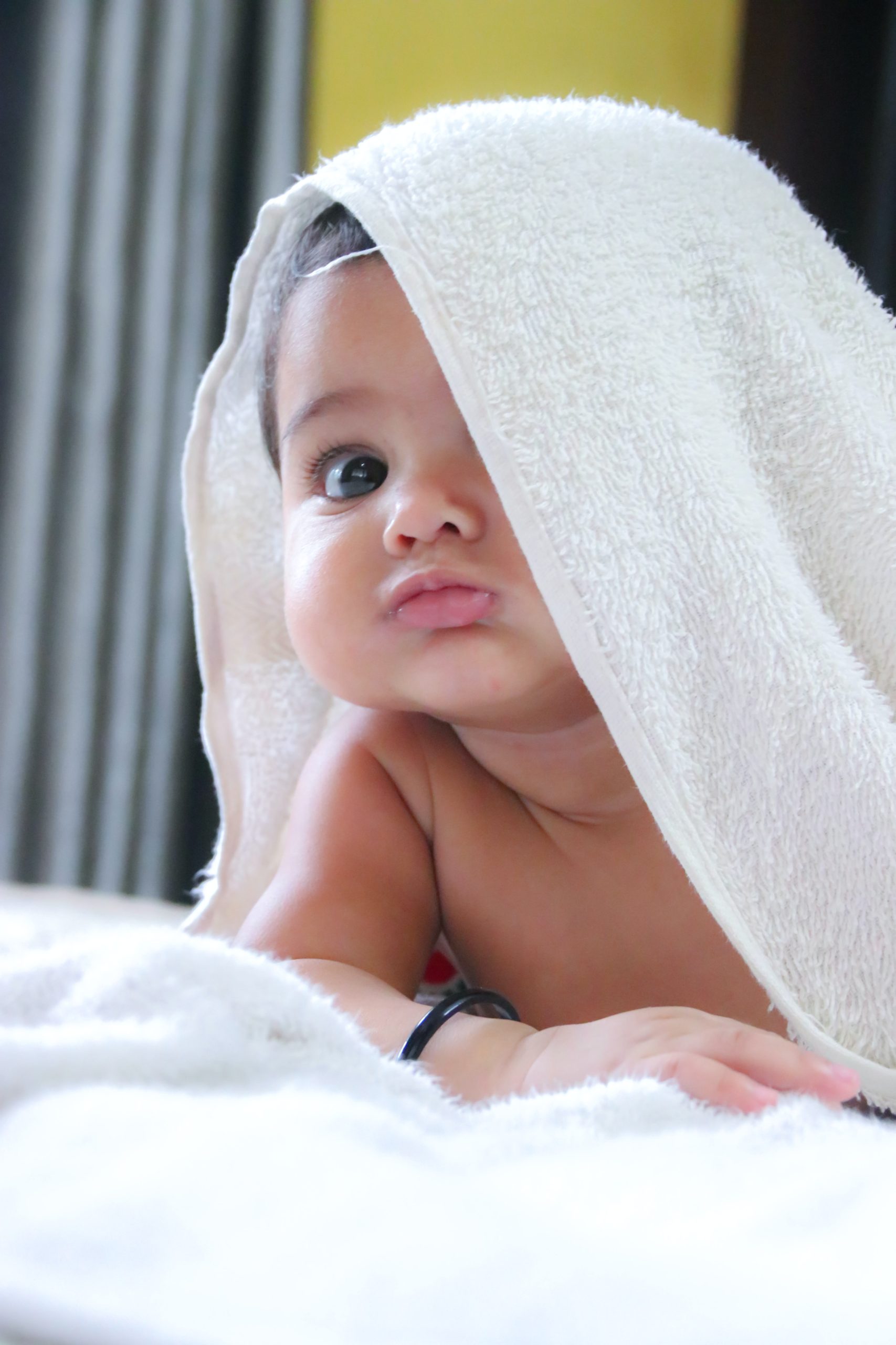 baby peeping from under white towel