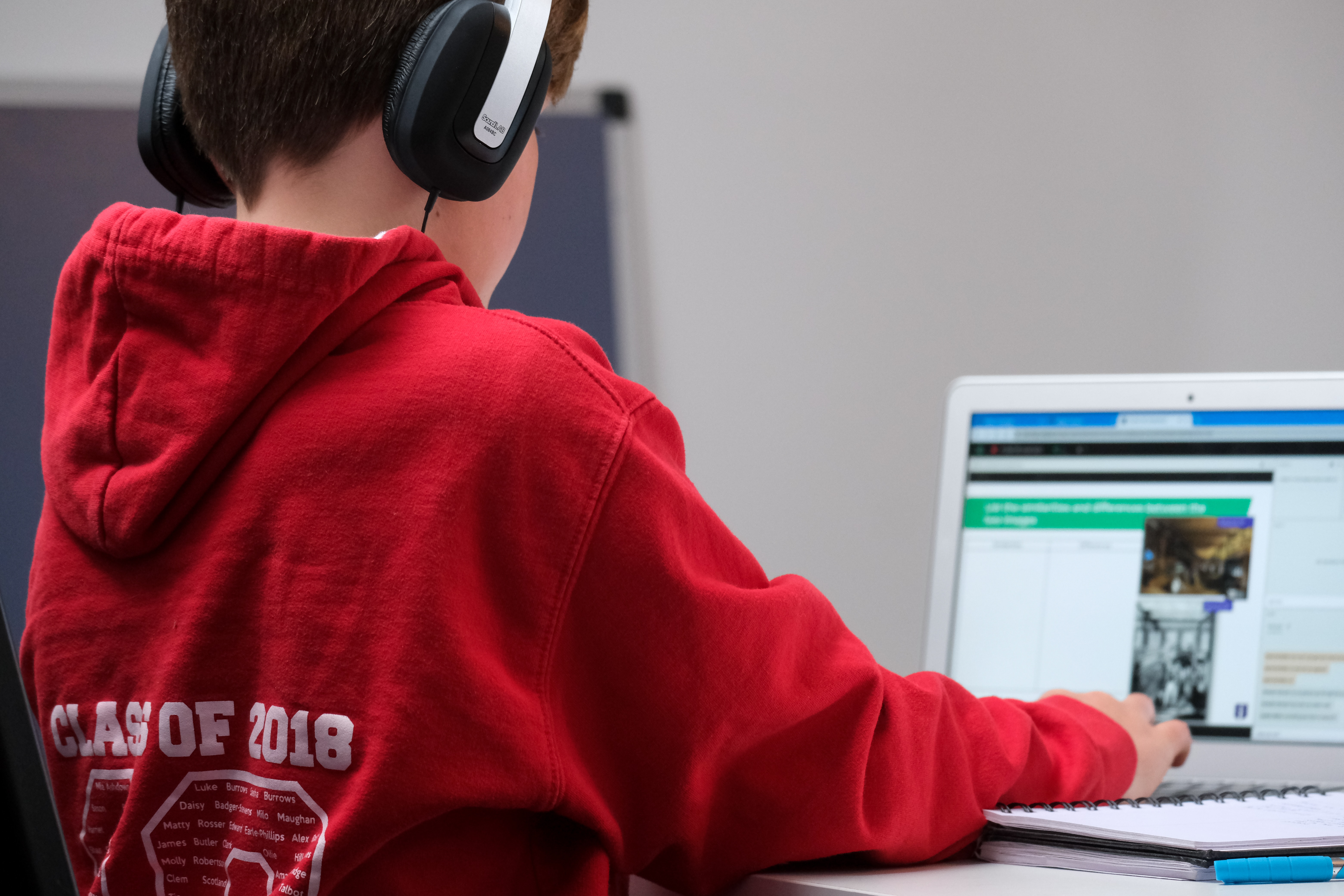 Boy in school leavers jumper works on a laptop