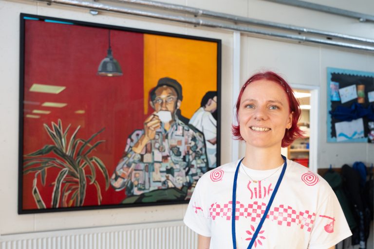Joy Labinjo’s Man drinking coffee from the Government Art Collection (GAC) on display in Pilgrim’s Way Primary School, Peckham, with GAC workshop leader, Silje Jorgensen.