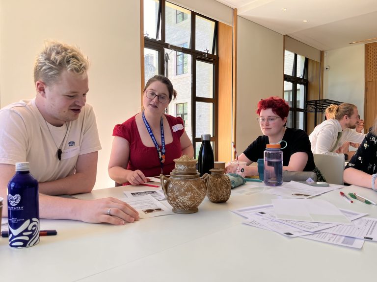 Three people examining two artefacts